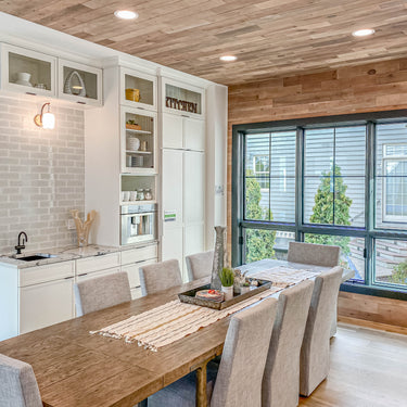 ET2 Soji lantern glass wall sconce on the kitchen wall beside a dining room with a wood-plank ceiling