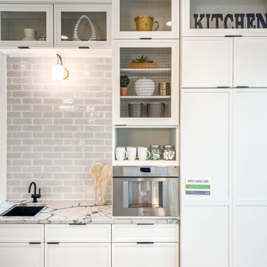 ET2 Soji lantern glass wall sconce lit over a kitchen counter with a coffee machine and white cabinets