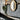 ET2 Floating round gold leaf frame mirror on a gray wall beside a potted plant and shelf