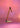 Mustard yellow Oluce Calamaio desk lamp with its arm raised, photographed against a pink backdrop