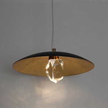Black and brass pendant light illuminating a dining room table