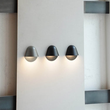 Three dark Penta Enoki wall sconces in a row on a wall