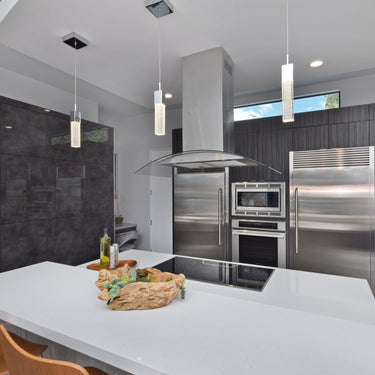 ET2 Fizz III bubble glass cube pendants hanging over a white kitchen island with orange chairs and a steel range hood