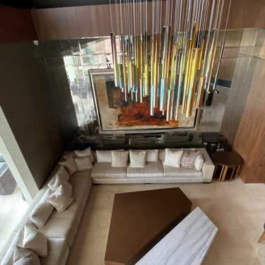 ET2 Flute gold and chrome tubes hung at varied heights over a sectional sofa in a tall living room