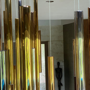 Close-up of ET2 Flute gold and chrome tubes of different lengths hanging beside a potted plant