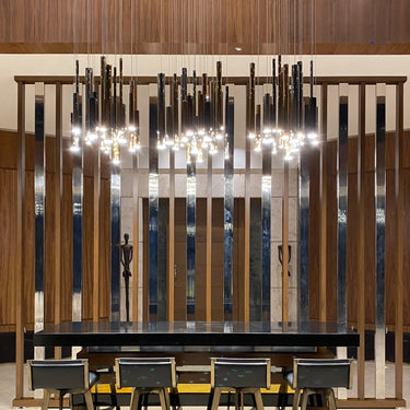ET2 Flute tubes hung over a dining area with a long wood-framed screen behind and black chairs below