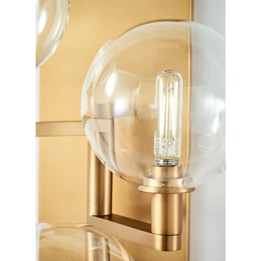LED 3-light Gambit wall sconce with borosilicate glass and aged brass finish in hallway setting