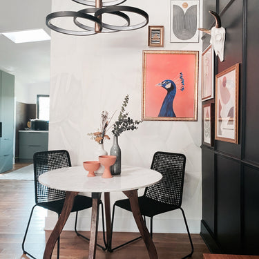 ET2 Hoopla ring pendant over a round white dining table with black chairs and pink wall art