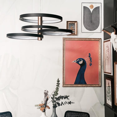 ET2 Hoopla ring pendant above a round dining table with a vase and a framed peacock print