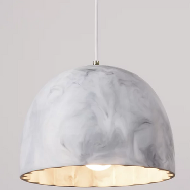 Innermost Doric 28 white marble look LED pendant light illuminating a minimalist bedroom.