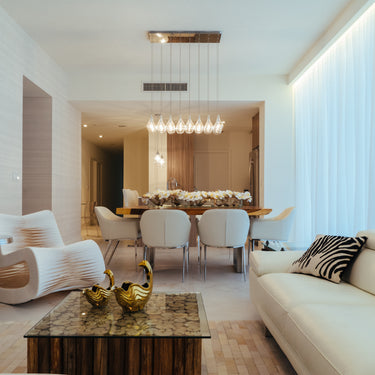 ET2 Larmes LED linear teardrop pendant over a dining table beside a living room with a white sofa