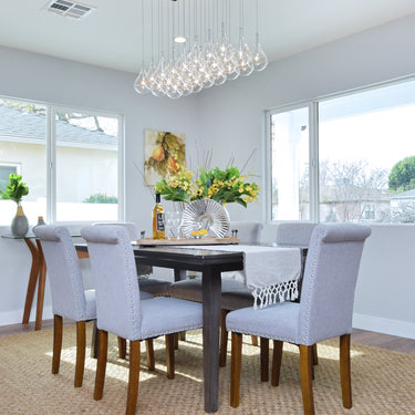 ET2 Larmes LED linear teardrop pendant over a dining table with gray upholstered chairs