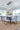 ET2 Larmes teardrop cluster under a rectangular canopy over a dining table with gray upholstered chairs and a jute rug
