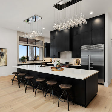 ET2 Larmes LED clear teardrop glass pendant cluster over a white kitchen island with black cabinets
