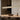 ET2 Lintel travertine linear pendant floating above a long wood dining table with brown chairs and a bowl, beige wall behind