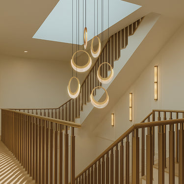 ET2 Lyra crescent pendants in Gold rings hanging through a wooden stairwell under a skylight