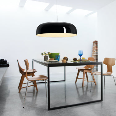 Oluce Canopy black pendant lamp over a dining table in a bright white room