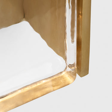 Industrial-style brass wall sconce with frozen water-textured glass shade.