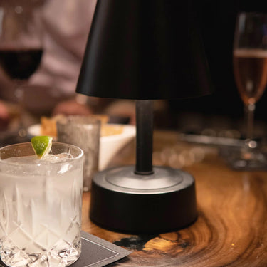 Mini Metal Outdoor Cordless Table Lamp Black by Modern Lantern illuminating patio