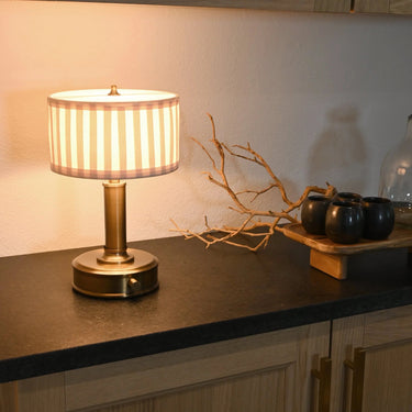 Mini Tito Cordless Table Lamp with pleated shade and antique brass finish in bedroom