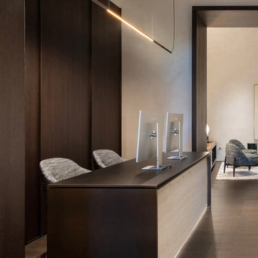 Ilo horizontal pendant above a dark reception counter in a showroom