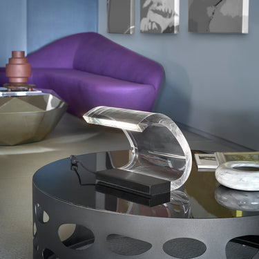 Oluce Acrilica lamp on a metal coffee table next to a purple armchair