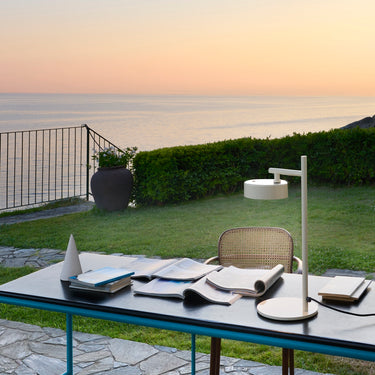 Oluce Berlin-Out table lamp on an outdoor dining table at sunset