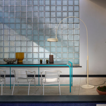 Oluce Berlin-Out arched floor lamp beside a glass dining table in a bright room