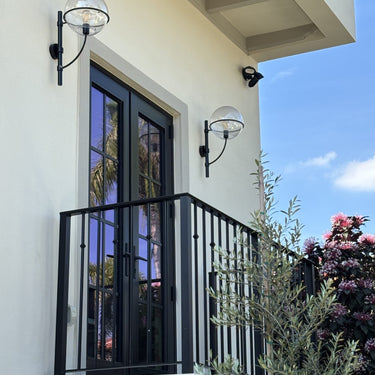 Lyndon outdoor wall lamp by Oluce beside a balcony window, lifestyle view