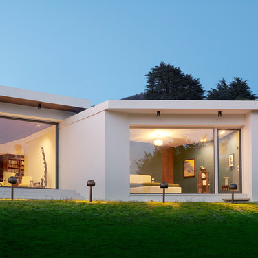 Oluce Otto path lights on a lawn in front of a modern house at dusk