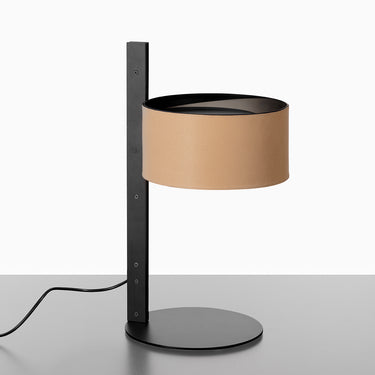 Oluce Parallel table lamp with a leather sand shade on a matt black stem against a white studio background