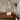 Oluce Pascal bronze floor lamp next to a brown sofa in front of a travertine wall