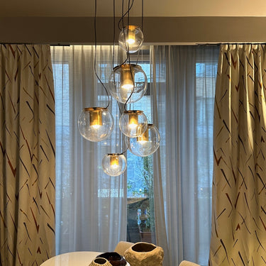 Cluster of Oluce The Globe glass pendants hanging in front of curtains