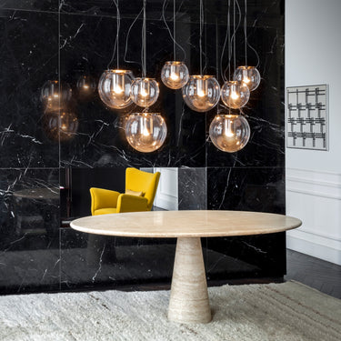 Oluce The Globe pendants hanging above a round dining table with a dark marble wall