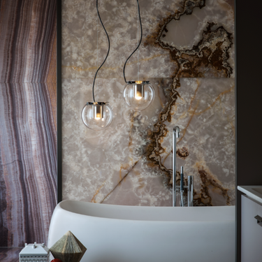 Oluce The Globe pendants hanging beside a bathtub and marble wall