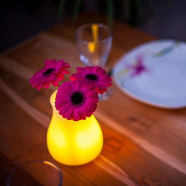 Olio Bluetooth LED Cordless Lamp by Smart & Green glowing yellow as a flower vase with magenta gerberas on a wood table - LoftModern