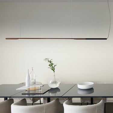 Ilo horizontal pendant by Oluce hung over a long dark dining table with white armchairs