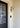Lyndon outdoor wall lamp by Oluce beside a front door, lifestyle view