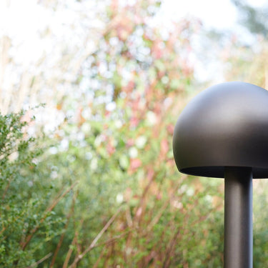 Close view of the Oluce Otto path light dome head and stem among garden plants