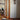 Oluce Pascal floor lamp in a wood-paneled room with a round table and an open doorway