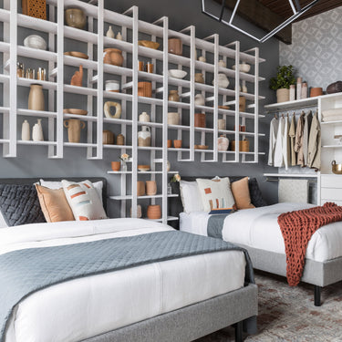 ET2 Penta black pentagon sphere pendant hanging over twin beds beside a white wall shelf in a bedroom