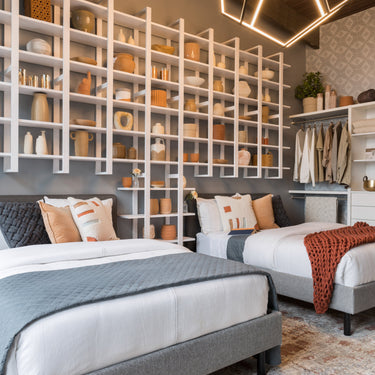 ET2 Penta LED pentagon sphere pendant glowing warm white over twin beds in a bedroom with a white wall shelf
