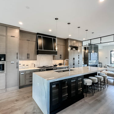 ET2 Pipette glass tube pendants over a kitchen island with gray cabinets and bar stools