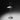 Regina T lamp lit in a dark room, casting a pool of indirect light on the surface below
