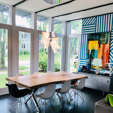 ET2 Rinkle pendant of hand-shaped acrylic sheets over a live-edge wood dining table in a sunroom with glass walls