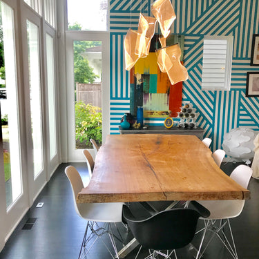 ET2 Rinkle acrylic sheet pendant above a wood slab dining table in front of a teal and white striped wall