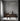ET2 Rollo tube pendant above a dark dining table in a room with a gray plaster wall