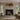 Cascata chandelier with a gold-toned frame and hanging glass panels in a living room with a fireplace and a curved sofa
