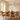 ET2 Scion branch pendant over a wood dining table with curved chairs beside a large window