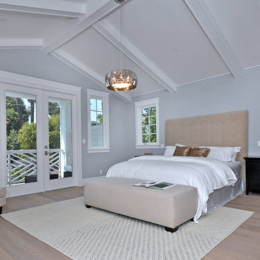ET2 Sense mirror chrome flush mount on a vaulted white ceiling above a bed with a tan tufted headboard and window
